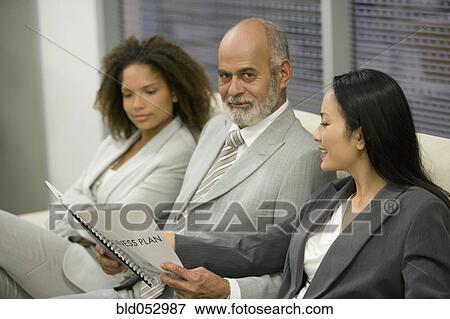 Stock Photo - Multi-ethnic businesspeople looking at paperwork. Fotosearch