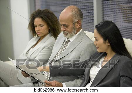 Multi-ethnic businesspeople looking at paperwork View Large Photo Image Stock Photograph - Multi-ethnic businesspeople looking at paperwork. Fotosearch