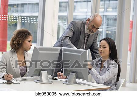 Multi-ethnic businesspeople looking at computer View Large Photo Image Stock Photography - Multi-ethnic businesspeople looking at computer. Fotosearch