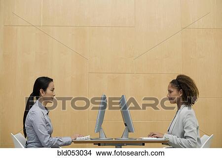 Picture - Multi-ethnic businesswomen typing on computers. Fotosearch