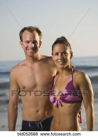 Stock Photo - Multi-ethnic couple hugging at beach. Fotosearch