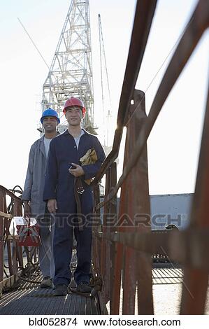 Multi-ethnic male construction workers in front of crane View Large Photo Image Picture - Multi-ethnic male construction workers in front of crane. Fotosearch