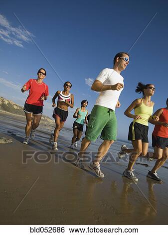 Stock Photograph - Multi-ethnic runners racing at beach. Fotosearch
