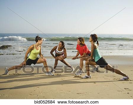 Picture - Multi-ethnic runners stretching at beach. Fotosearch