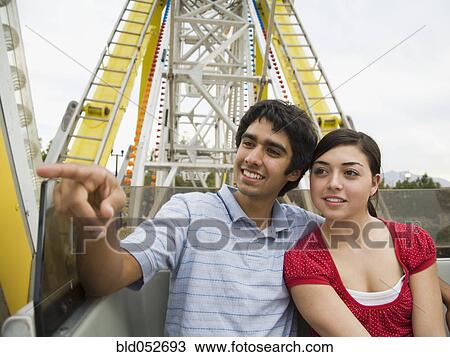 Stock Image - Multi-ethnic teenaged couple on carnival ride. Fotosearch