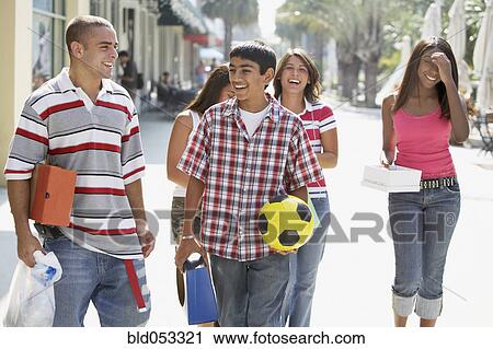 Stock Image - Multi-ethnic teenagers walking on sidewalk. Fotosearch