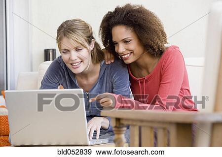 Stock Photo - Multi-ethnic women looking at laptop. Fotosearch