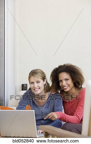 Stock Image - Multi-ethnic women next to laptop. Fotosearch