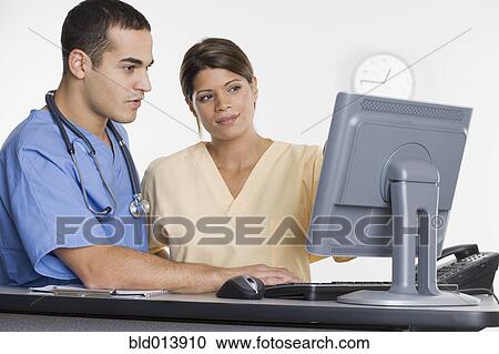 Stock Image - Nurses looking at computer monitor. Fotosearch