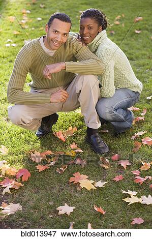Portrait of couple kneeling in park View Large Photo Image Stock Photo - Portrait of couple kneeling in park. Fotosearch