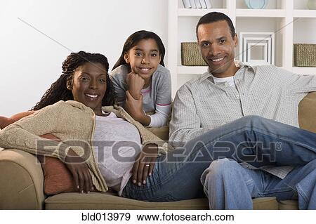Stock Photo - Portrait of family sitting on couch. Fotosearch