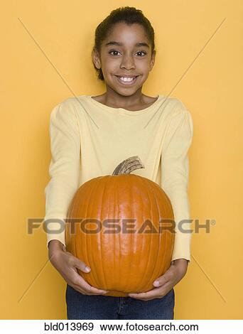 Stock Photo - Portrait of girl holding pumpkin. Fotosearch