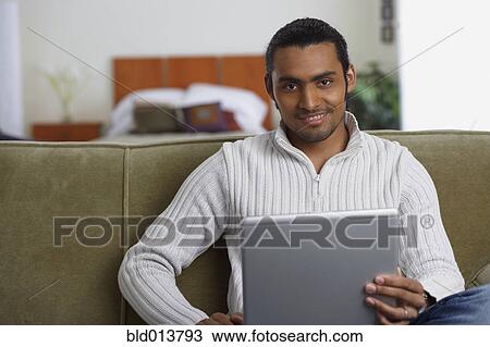 Portrait of man sitting on couch with computer View Large Photo Image Stock Image - Portrait of man sitting on couch with computer. Fotosearch