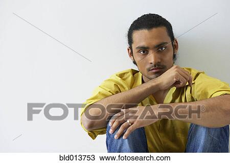 Stock Image - Portrait of man sitting on floor. Fotosearch