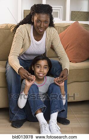Portrait of mother and daughter sitting in living room View Large Photo Image Stock Photo - Portrait of mother and daughter sitting in living room. Fotosearch
