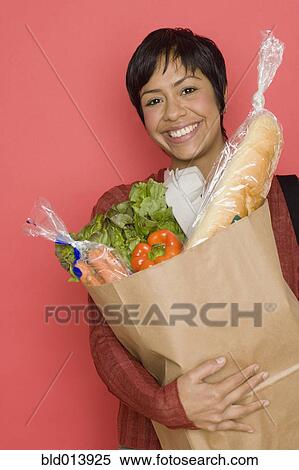 Stock Photography - Portrait of woman holding bag of groceries. Fotosearch
