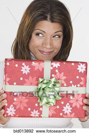 Stock Image - Portrait of woman holding gift and looking up. Fotosearch