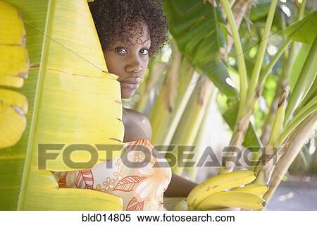 Stock Photography - Portrait of woman in banana tree holding bananas. Fotosearch