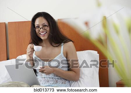 Portrait of woman in bed with laptop drinking coffee View Large Photo Image Stock Image - Portrait of woman in bed with laptop drinking coffee. Fotosearch