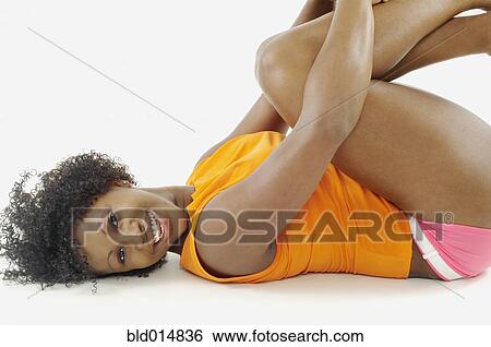 Stock Photograph - Portrait of woman laying down with arms wrapped around knees. Fotosearch
