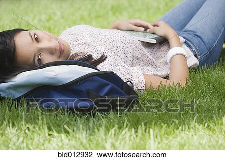 Stock Image - Portrait of woman laying in grass. Fotosearch