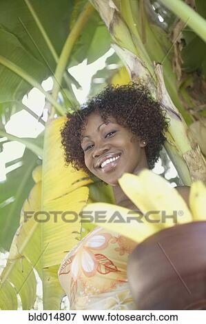 Portrait of woman standing in front of tree with bananas View Large Photo Image Stock Photo - Portrait of woman standing in front of tree with bananas. Fotosearch