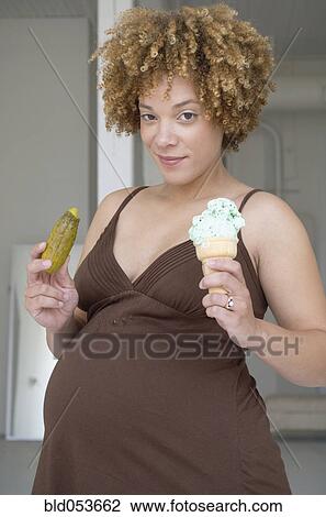 Pregnant African woman holding pickle and ice cream View Large Photo Image Stock Image - Pregnant African woman holding pickle and ice cream. Fotosearch