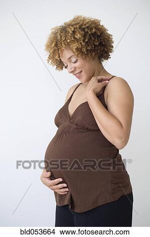 Pregnant African woman smiling at belly View Large Photo Image Picture - Pregnant African woman smiling at belly. Fotosearch
