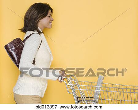 Stock Photo - Profile of woman pushing shopping cart. Fotosearch