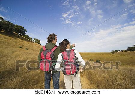 Stock Image - Rear view of couple hiking and pointing. Fotosearch