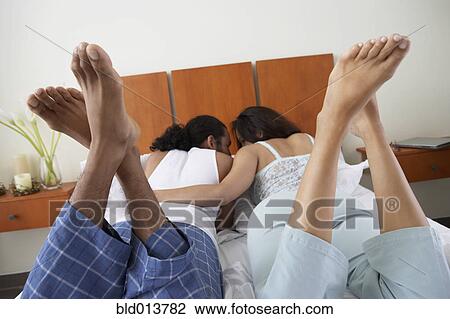 Rear view of couple laying in bed with feet up View Large Photo Image Stock Image - Rear view of couple laying in bed with feet up. Fotosearch