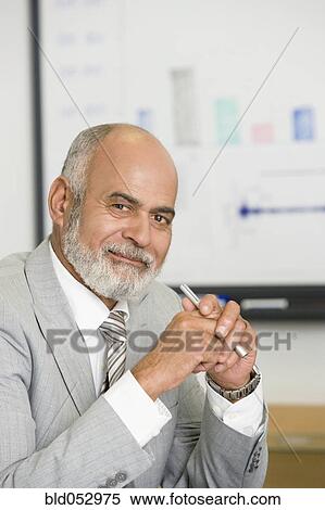 Stock Photography - Senior African businessman holding pen. Fotosearch