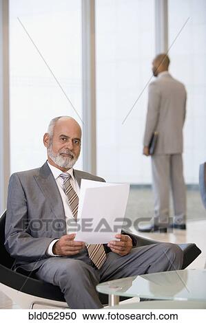 Stock Image - Senior African businessman holding paperwork. Fotosearch