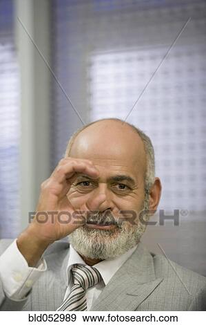 Stock Photo - Senior African businessman looking through circled hand. Fotosearch