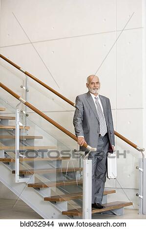 Picture - Senior African businessman standing on stairs. Fotosearch