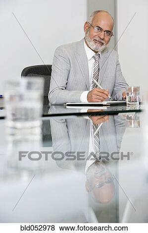 Stock Photo - Senior African businessman writing at table. Fotosearch