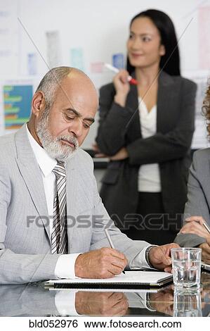 Stock Photograph - Senior African businessman writing at table. Fotosearch