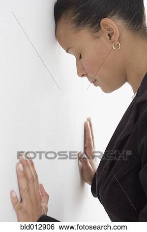 Stock Photograph - Side view of businesswoman leaning against wall with eyes closed. Fotosearch