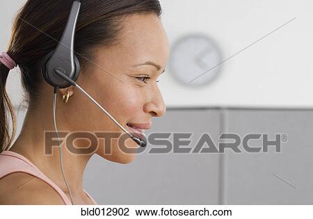 Stock Image - Side view of woman in office with headpiece. Fotosearch