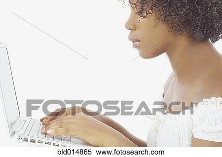 Stock Photography - Side view of woman typing on laptop. Fotosearch
