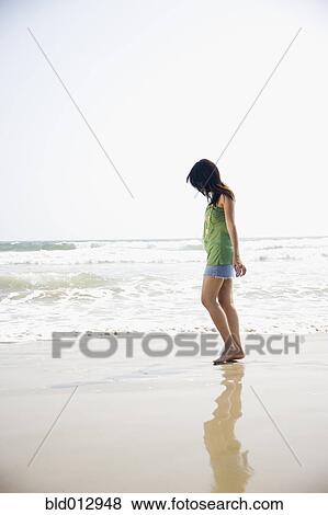 Stock Photo - Side view of woman walking on beach. Fotosearch