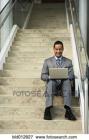 Smiling businessman on steps with laptop View Large Photo Image Stock Photo - Smiling businessman on steps with laptop. Fotosearch