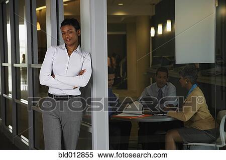 Smiling woman with colleagues in background View Large Photo Image Stock Photography - Smiling woman with colleagues in background. Fotosearch