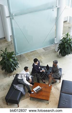 Three businesspeople meeting in lobby View Large Photo Image Stock Photo - Three businesspeople meeting in lobby. Fotosearch