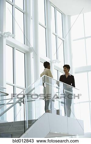 Stock Image - Two businesswomen talking. Fotosearch