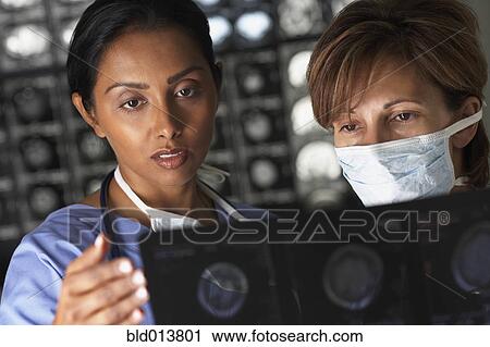 Two female doctors looking at x-rays View Large Photo Image Stock Image - Two female doctors looking at x-rays. Fotosearch