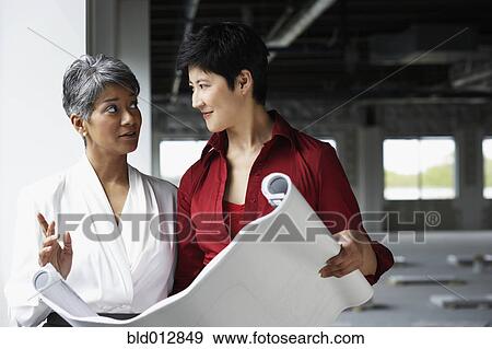 Stock Photo - Two women conferring at construction site. Fotosearch