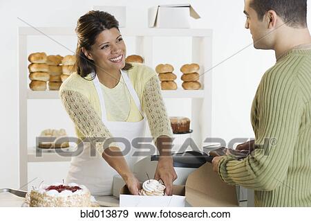 Stock Photo - Woman at bakery helping customer. Fotosearch