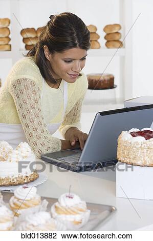 Woman at bakery working on laptop View Large Photo Image Stock Image - Woman at bakery working on laptop. Fotosearch