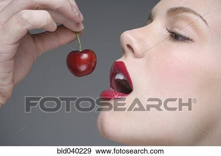 Stock Photo - Woman eating cherry. Fotosearch
